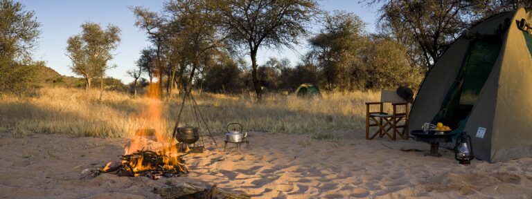 Abenteuerliches Safari-Camp in Afrika mit Zelten, Lagerfeuer, Natur und Tierbeobachtungserlebnis.