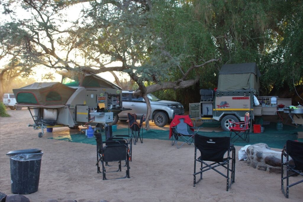 2. Geräumiges Safari-Camp oase mit Zelten, Camping-Tischen und Wildtiere in Afrika, ideal für Natur- und Abenteuertouren.