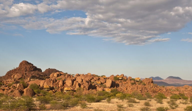 AltText: Wüstenlandschaft in Afrika mit Felsen und Sand, unter blauem Himmel und Wolken.