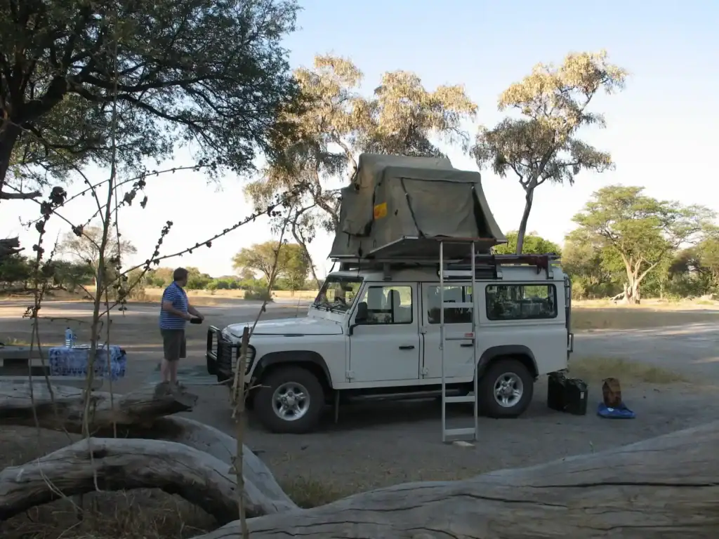 Altes Land Rover mit Dachzelt im afrikanischen Busch, perfekt für Safari und Wildbeobachtung.