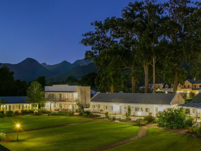 Lodge in Afrika mit grünem Garten und Bergen im Hintergrund, ideal für eine Safari in Afrika.