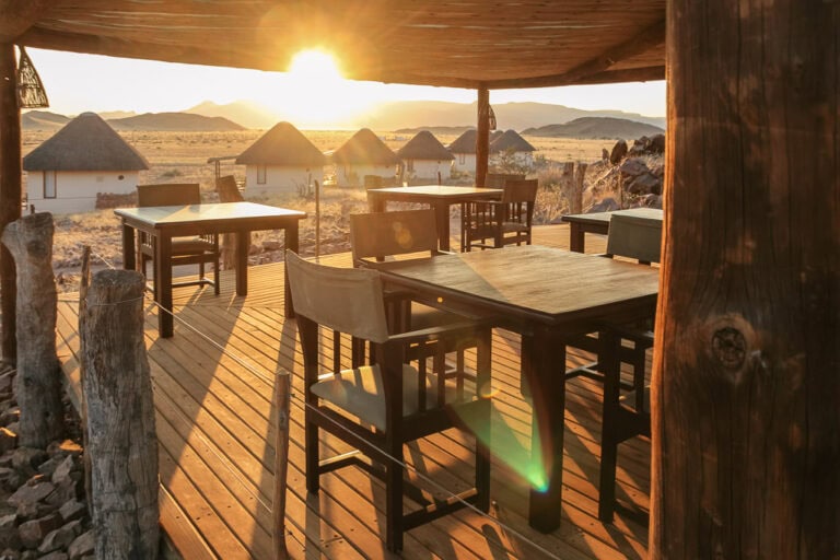 Gemütliche Lodge-Terrasse mit Blick auf die Savanne bei Sonnenuntergang in Afrika, ideal für Safari-Reisen.