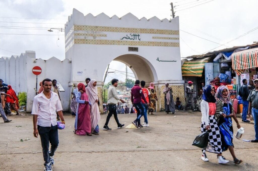 Flughafen in Afrika mit Passagieren und Markt im Hintergrund.