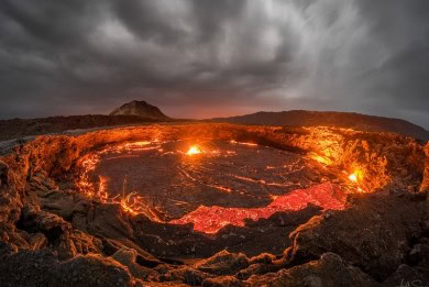 Vulkan mit Lavafluss bei Sonnenuntergang in Afrika, beeindruckende Naturkulisse.