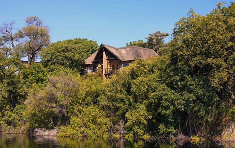 Luxus Safari Lodge inmitten grüner Natur mit Blick auf den Fluss, ideal für Afrikareisen.