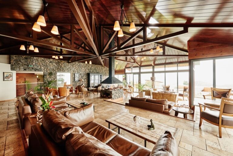 Gemütliche Lounge in einem afrikanischen Safari-Resort mit Holzdecke und Panoramafenstern.