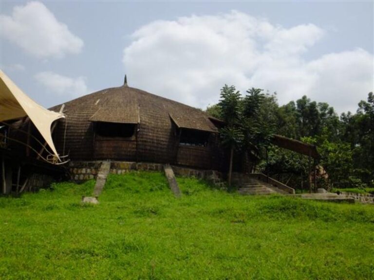 Traditionelles afrikanisches Holzhaus inmitten grüner Natur, perfekt für Afrika Rundreisen.