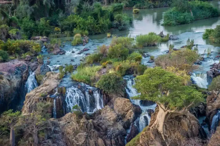 Ein malerischer Wasserfall in der südafrikanischen Wildnis, umgeben von üppigem Grün.