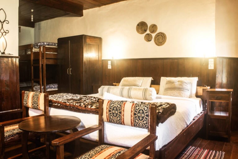 Gemütliches Gästezimmer mit afrikanischem Holzdekor, Betten und traditionellem Ambiente.