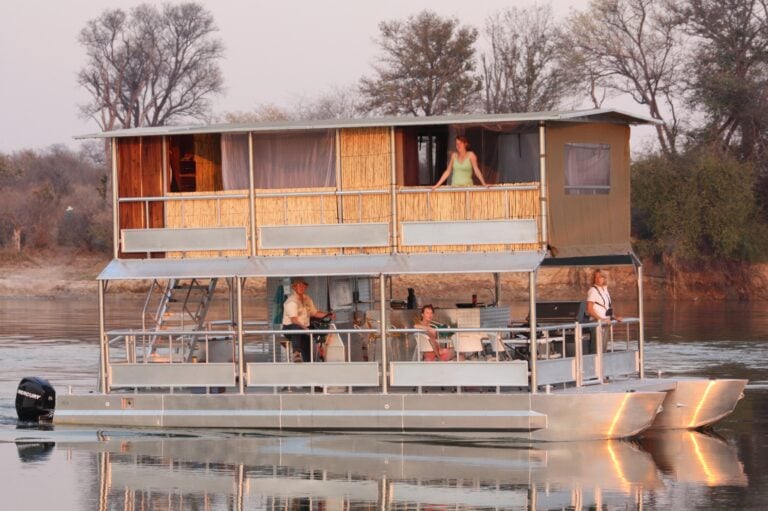 Hausboot auf Fluss mit Landschaft und Menschen, Safari, Flusskreuzfahrt in Afrika, Natururlaub.