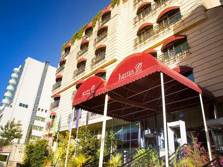 Alt: Modernes Hotel mit rotem Eingangsvordach in Afrika, ideal für Afrika Reisen.