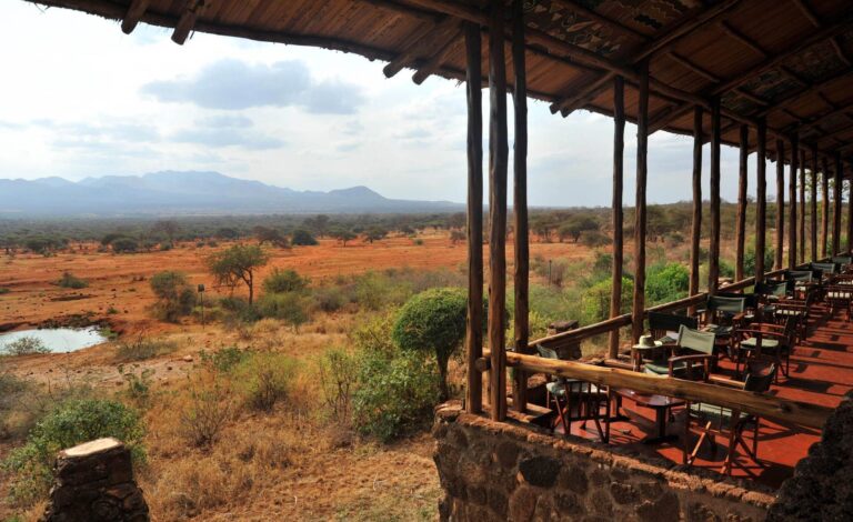 Panoramaaufnahmen einer Lodge in Afrika mit Blick auf die weite Savanne, wild lebende Tiere und Berge im Hintergrund.