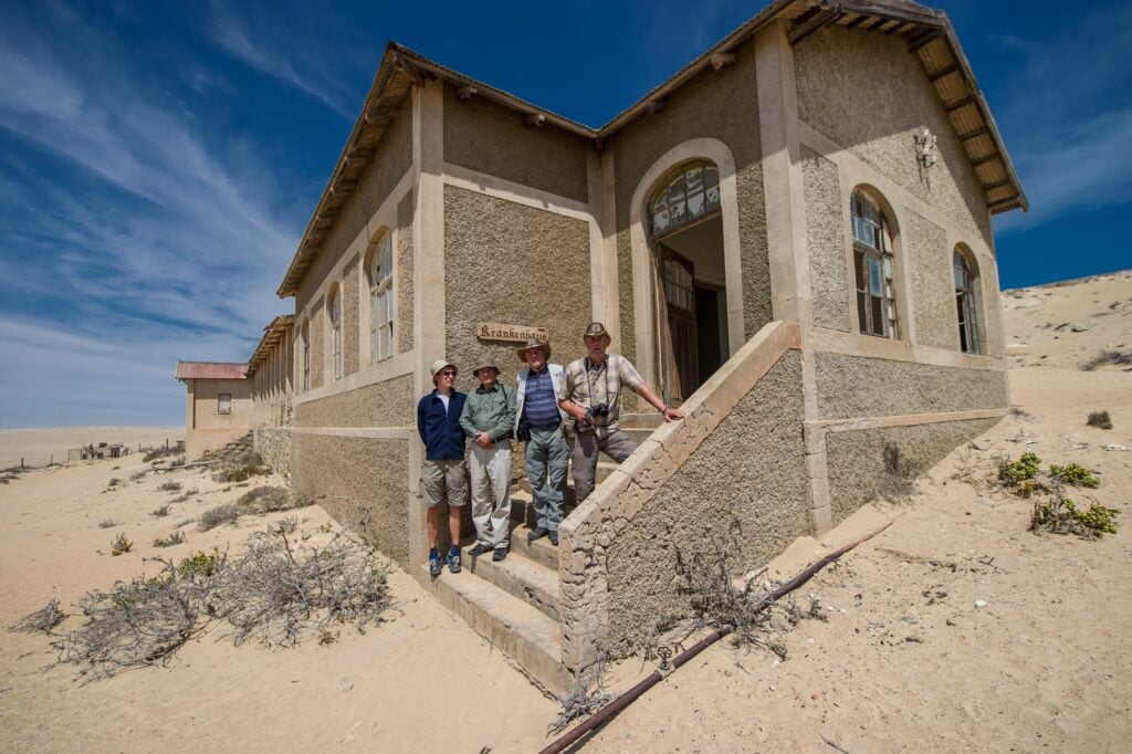 Alter, verfallener Klinikbau in der Wüste mit Touristen vor der Tür, Afrika Reiseabenteuer.
