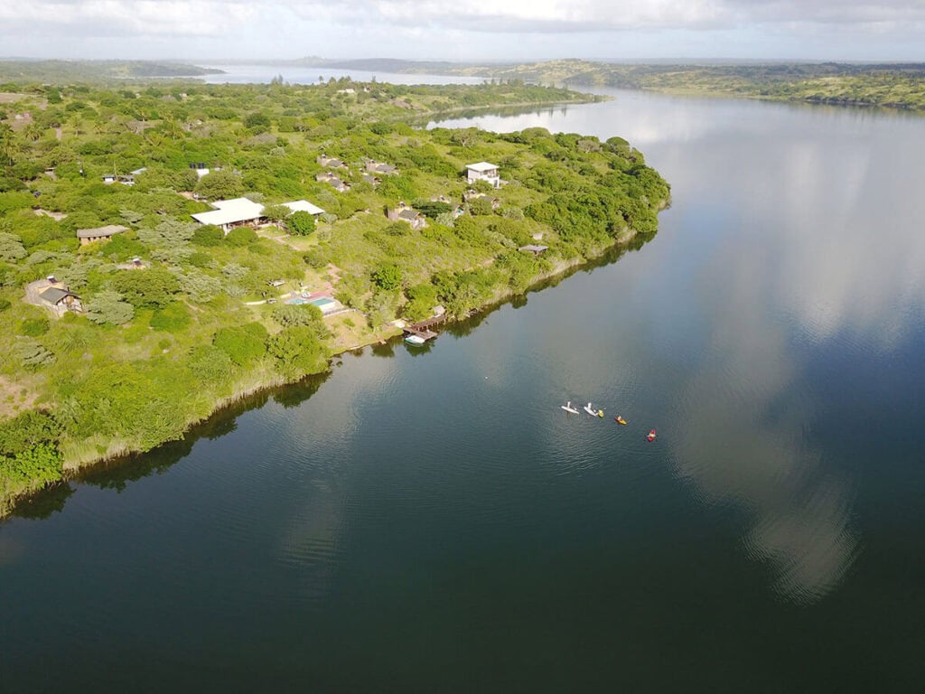 Schwimmende Boote auf einem afrikanischen Fluss mit grüner Uferlandschaft.