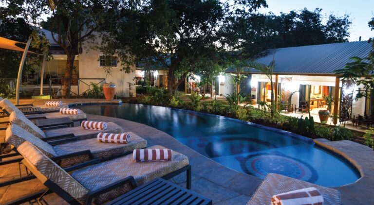 Pool mit Sonnenliegen in einer afrikanischen Lodge, Abendstimmung im Safari-Resort.