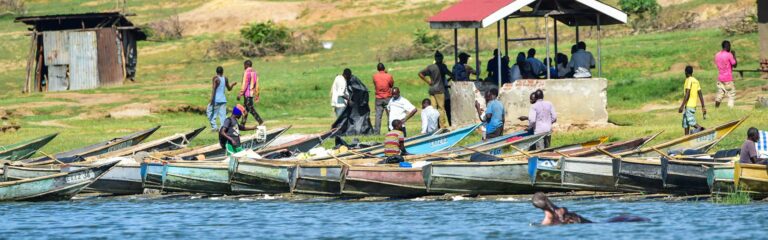 Menschen am Ufer des Tanganjika-Sees in Afrika, mit traditionellen Booten, Insel- und Seelandschaft, Afrika-Reiseabenteuer, Natur und Kultur.