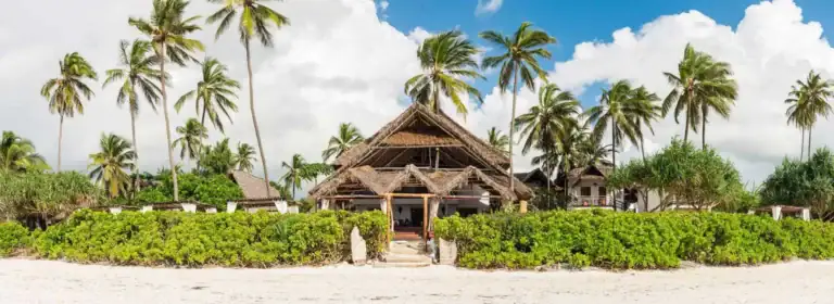 Strand mit Palmen und thatargetauchtem Bungalow in Afrika.