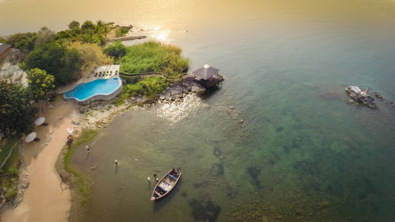 Heller Blick auf eine afrikanische Küstenregion mit Pool, Booten und malerischer Natur.