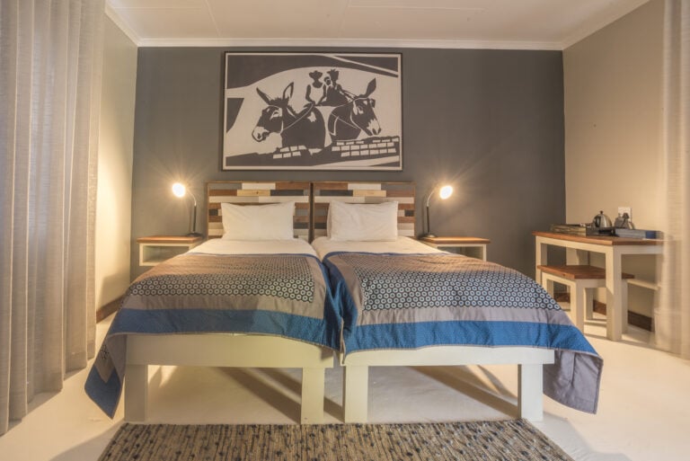 Gemütliches Safari Lodge Schlafzimmer mit afrikanischem Dekor, komfortablen Betten und kreativen Wandkunstwerken für Afrika-Urlaub.