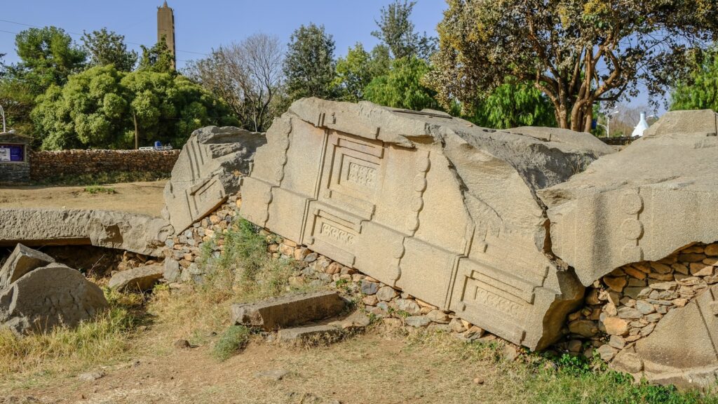 Steinmammut in Afrika, archäologisches Ausstellungsstück vor Bäumen, Sandboden.