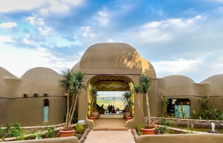 Alt Text: Traditionelles afrikanisches Haus im Wüstendesign mit Palmen, Teakholz und afrikanischer Architektur.