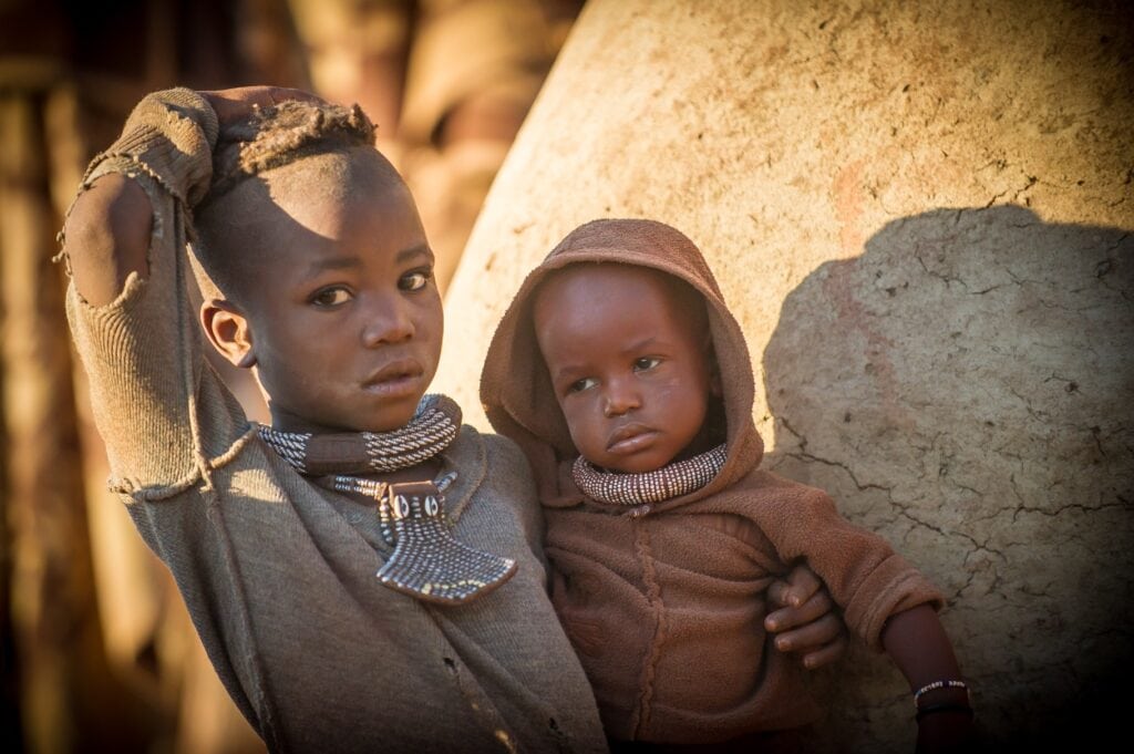 Junge afrikanische Kinder in traditioneller Kleidung in der Savanne.