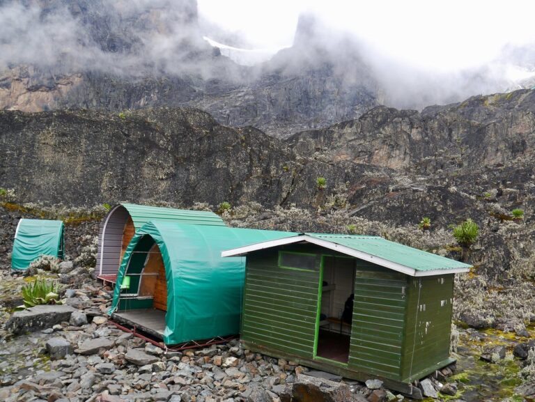 Zelt und Hütte in alpiner Landschaft, ideal für Afrika Safari und Naturerlebnis.