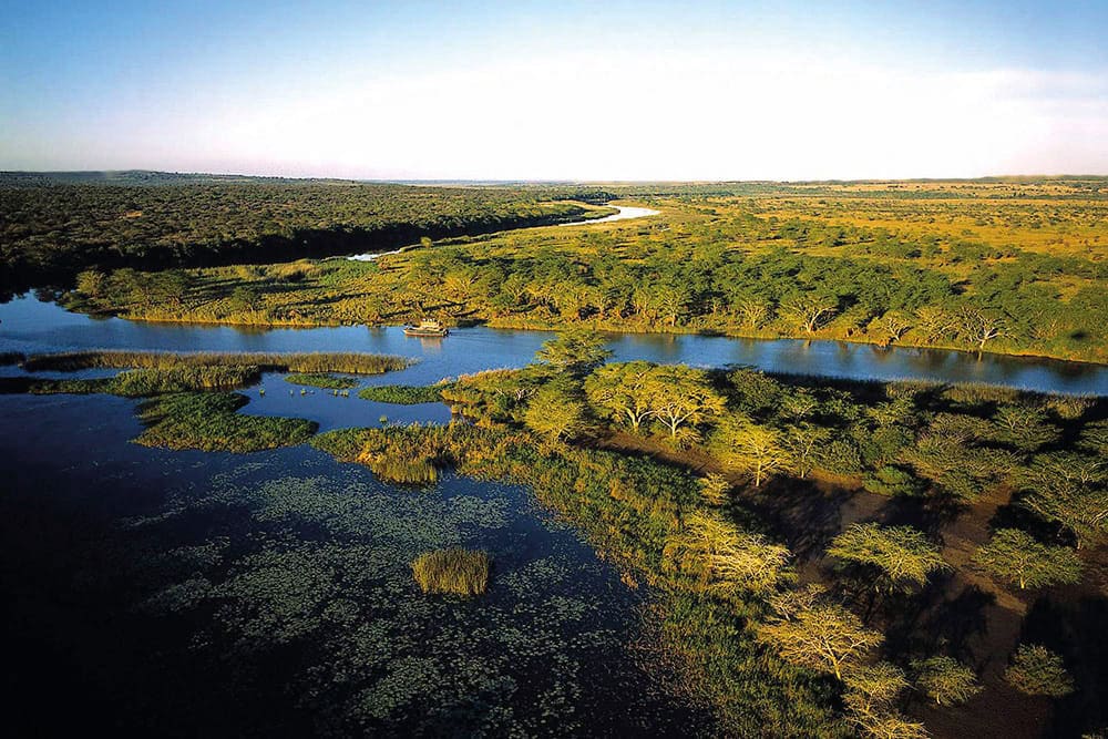 Alt Text: Afrikanische Flusslandschaft im Okavango-Delta mit Wasser, Bäumen und Tierwelt.