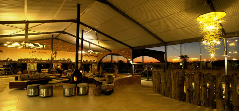 Helle, elegante Safari-Lodge mit afrikanischem Stil, Sonnenuntergang im Hintergrund, perfekte Afrika-Reise.
