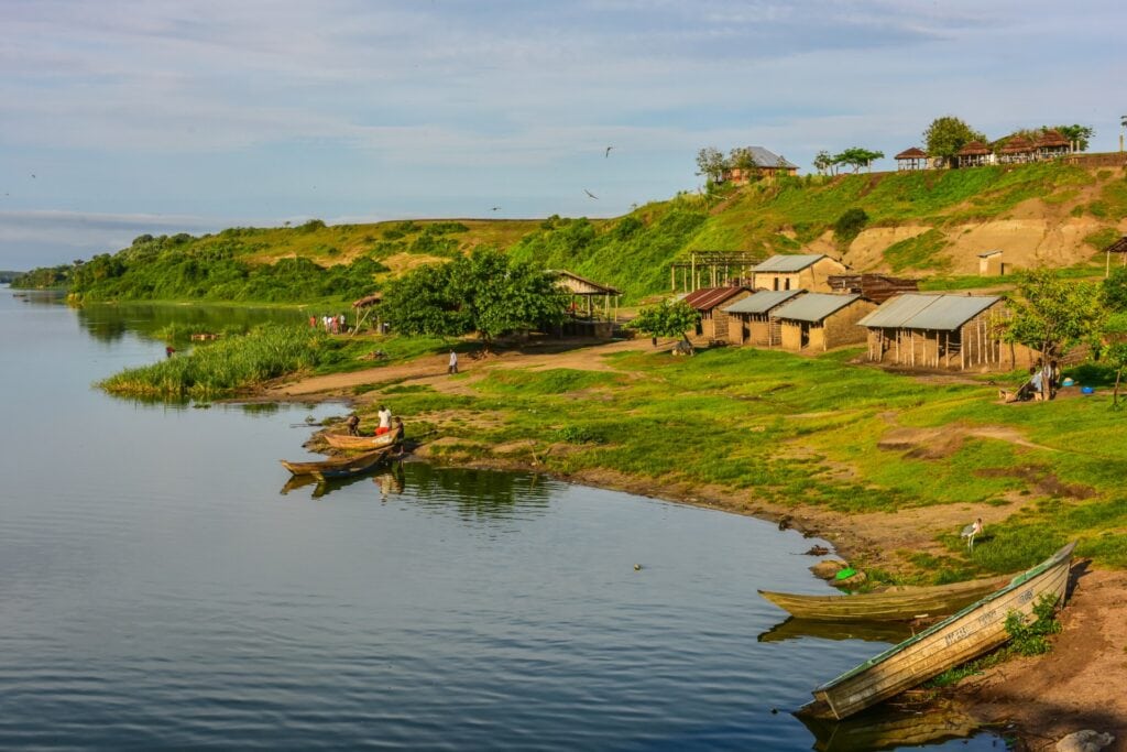 Blick auf Fluss, traditionelle afrikanische Hütten, Natur, Dörfliches Leben, Afrika-Reise.