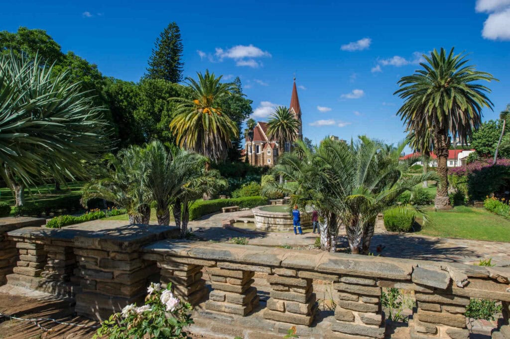 Saftige Palmen und ein Kirchenbau in einem afrikanischen Garten, sonniger Tag.