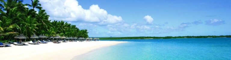 Ein idyllischer afrikanischer Strand mit Palmen, Sonnenschirmen und türkisfarbenem Wasser.