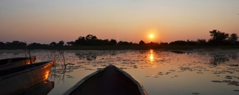 Sonnenuntergang am afrikanischen Fluss mit Booten, ideal für Safari und Natururlaub in Afrika.