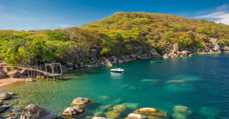 Idyllischer Blick auf einen klaren, blauen See umgeben von grünen Bäumen und Felsen in Afrika.