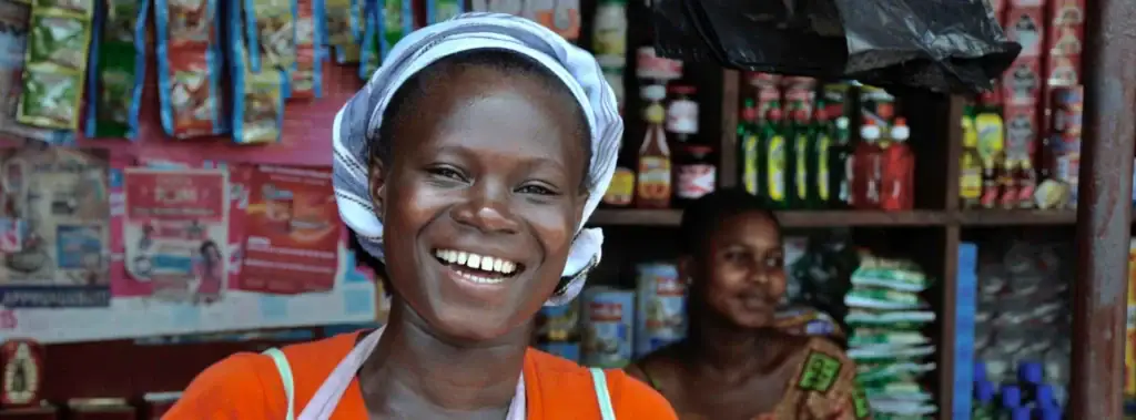 Frohe afrikanische Frau in Markt, bunte Souvenirs, lokale Kultur, authentische Reiseerlebnisse.