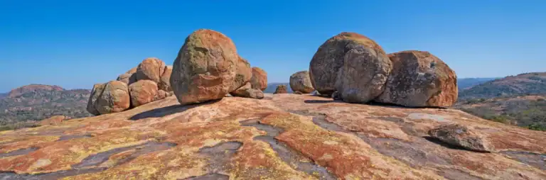 Felsformation in der Saharawüste mit großen Steinen und blauem Himmel.