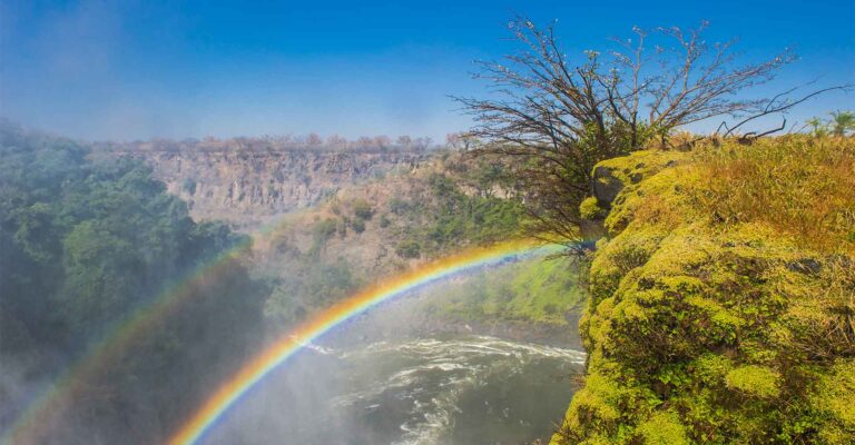 Farbintensiver Wasserfall mit Regenbogen und beeindruckender afrikanischer Landschaft.