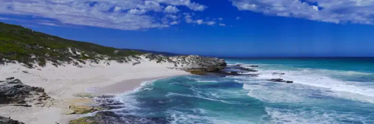 Traumstrand auf Sansibar, flaches Wasser, weißer Sand, üppige grüne Landschaft, ideal für Afrika Reiseabenteuer.