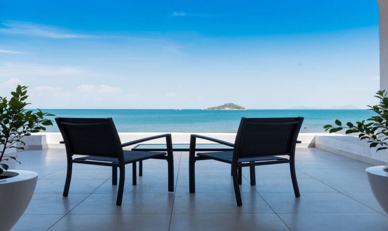 Alt Text: Zwei schwarze Stühle auf einer weißen Terrasse mit Meeresblick in Afrika.