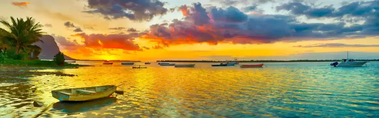 Bunte Boote am weißen Sandstrand bei Sonnenuntergang in Afrika.
