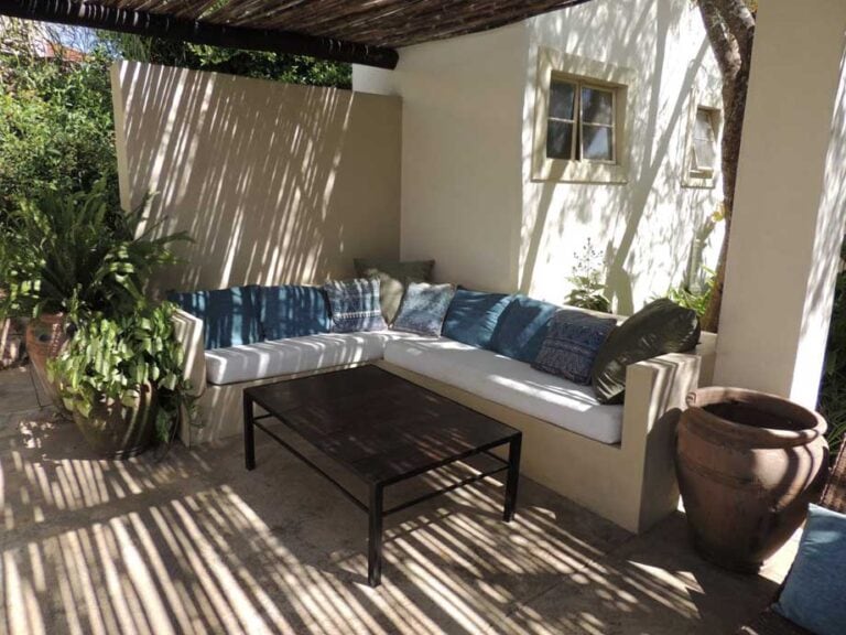 Gemütliche afrikanische Outdoor-Lounge mit Palmen und Schatten.
