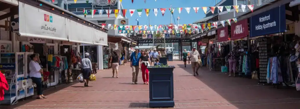 Bunter Markt in Südafrika mit Touristen, Souvenirständen und Flaggen, ideal für Afrika Reisen.