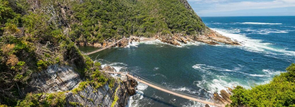Atemberaubende afrikanische Küste mit Wasser, üppigem Grün und Weg entlang der Klippen.