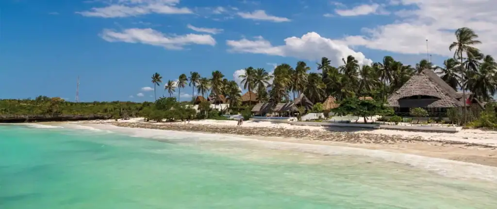 Hotelsterne auf Sansibar – Was wirklich zählt 1 Strand mit Palmen, Tiki-Hütten, türkisblauem Wasser, Sonnenuntergang, exotisches Afrika-Reiseparadies.