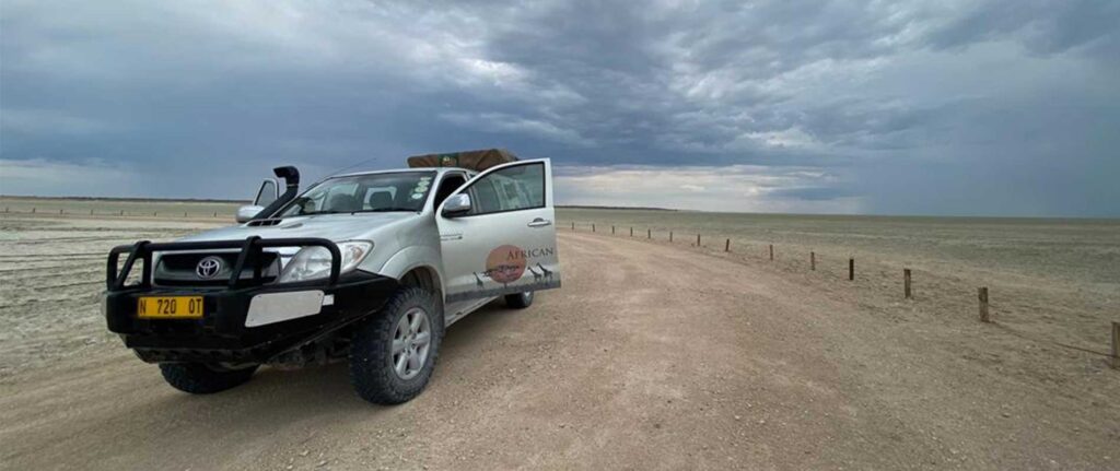 Robustes Safari-Fahrzeug in der Wüste vor dunklem Himmel, optimal für Afrika Reisen und Wildbeobachtung.