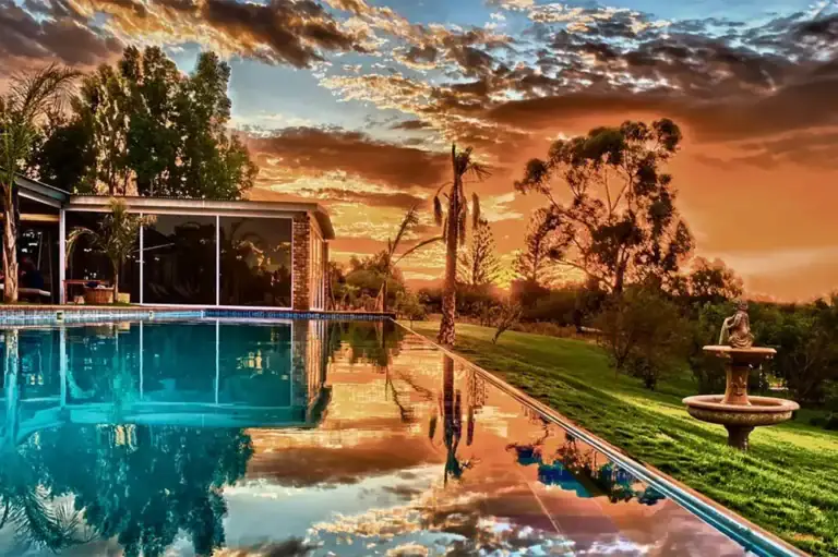 Erholung im afrikanischen Luxusresort mit Pool, tropischer Vegetation und Sonnenuntergang.