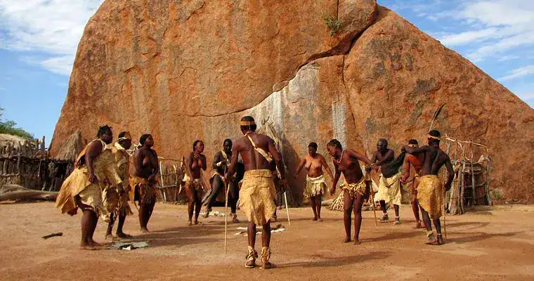 Menschen in traditionellen afrikanischen Gewändern bei einer Ritualzeremonie.