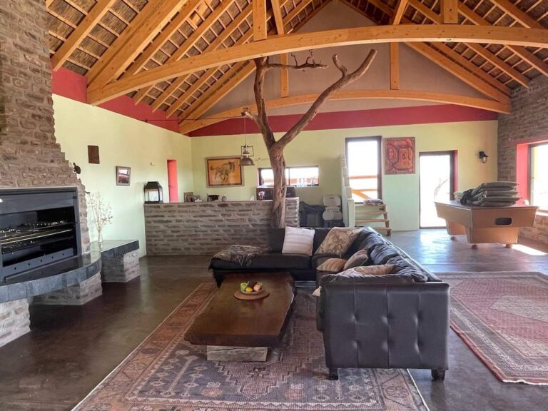 Gemütlicher Wohnraum in afrikanischem Stil mit Holzdecke und eingezogenem Baum in Namibia.