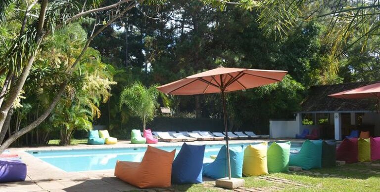 Entspannen am Pool im Luxus Afrika-Resort mit Sonnenliegen und bunten Sitzsäcken, umgeben von Palmen.