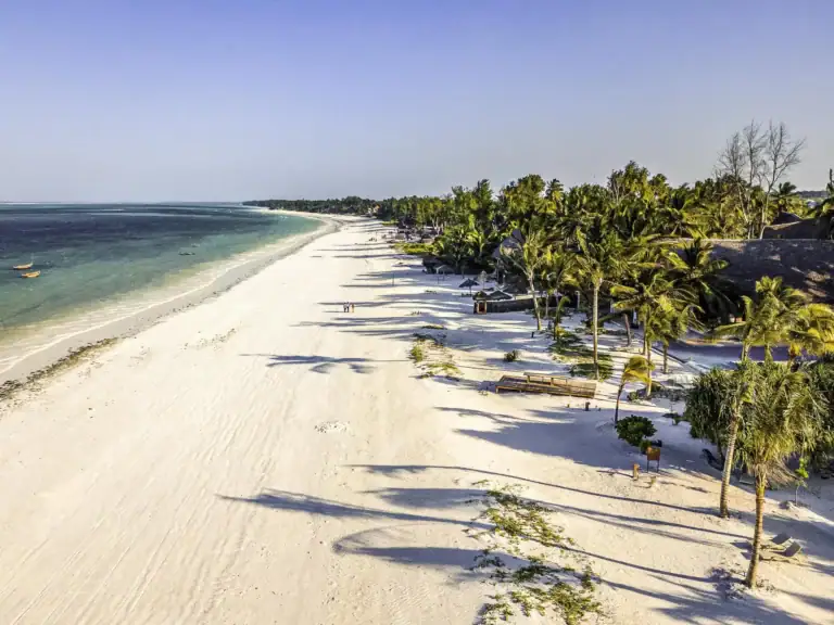 Strand in Afrika mit weißen Sand, Palmen und Meeresblick.